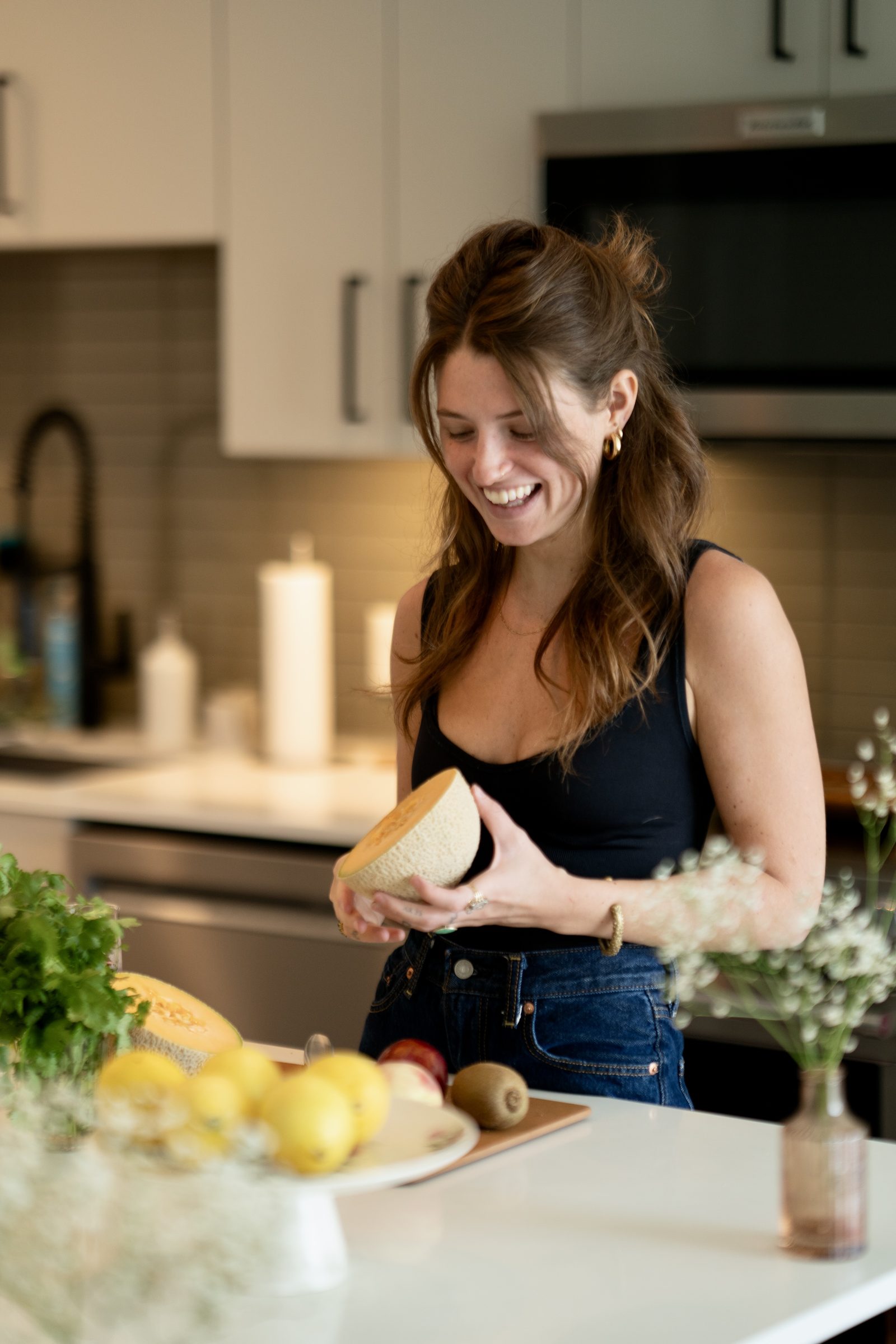 Lilith preparing fruit in a kitchen, smiling