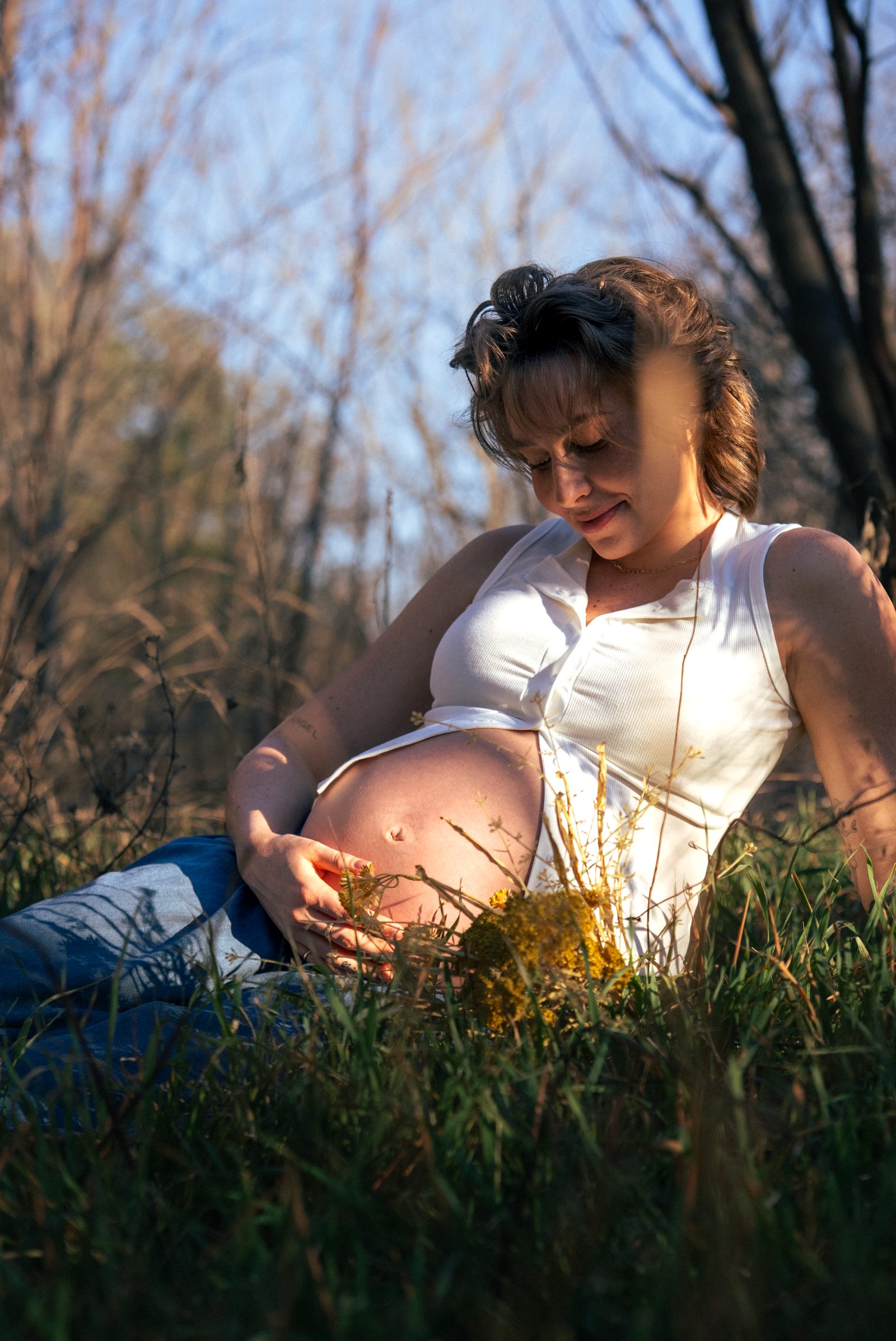 Lilith, pregnant, sitting in a sunlit field